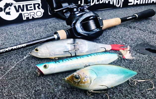 Large bass lures lined up on a boat carpet